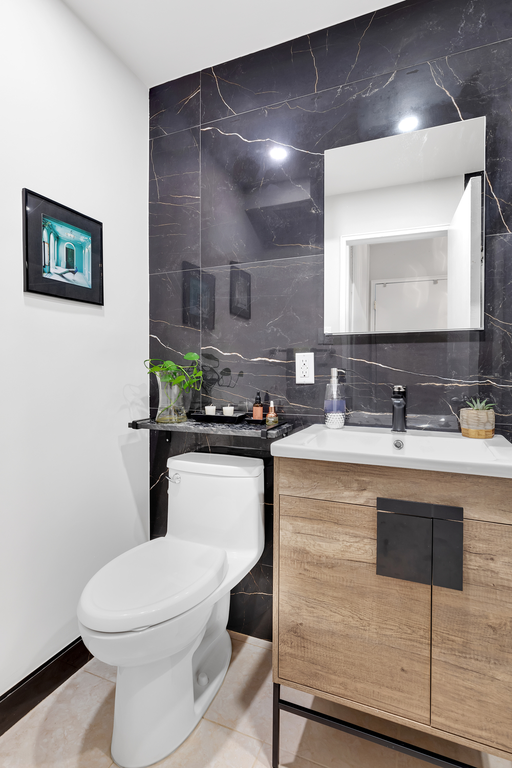 Luxury modern bathroom with dramatic black porcelain slabs featuring gold veining, custom walnut vanity, matte black fixtures, and frameless glass shower – Murray Hill Manhattan by SABI Construction