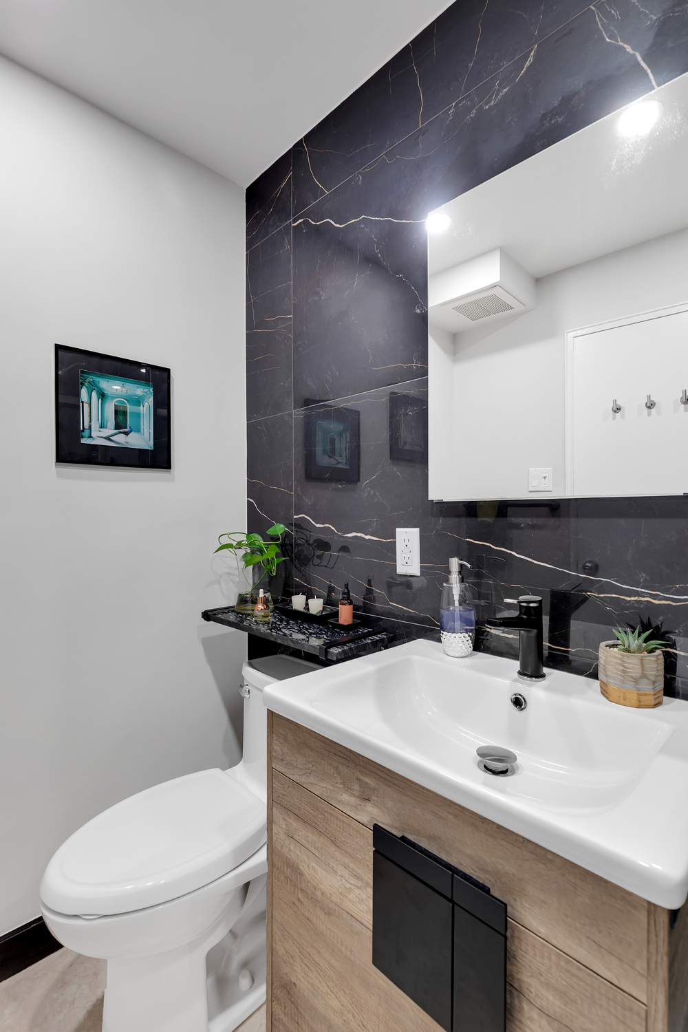 Luxury modern bathroom with dramatic black porcelain slabs featuring gold veining, custom walnut vanity, matte black fixtures, and frameless glass shower – Murray Hill Manhattan by SABI Construction