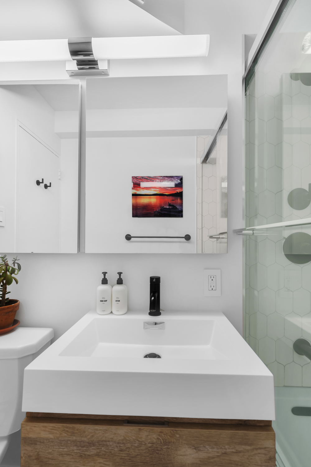 Luxury modern bathroom renovation Upper East Side Manhattan with wall-mounted walnut vanity, charcoal large-format floor tile, white subway wall tile, and alcove bathtub