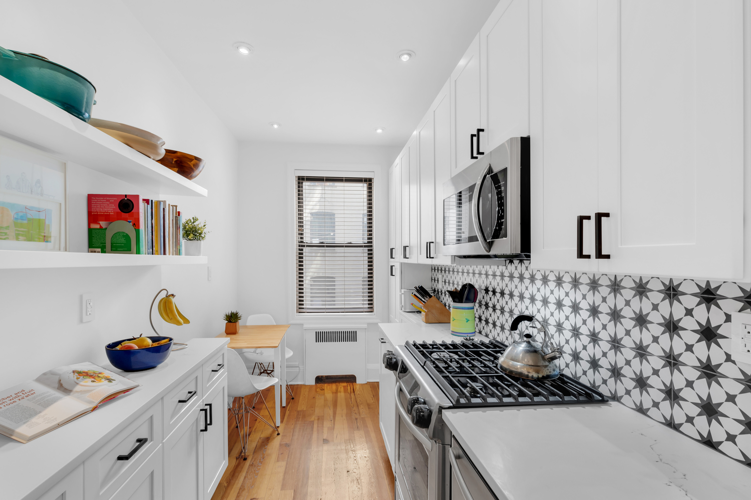 Luxury white shaker kitchen with matte black hardware, black-and-white star tile backsplash, quartz countertops, and hardwood floors – full renovation in Prospect Park Southwest, Brooklyn by SABI Construction