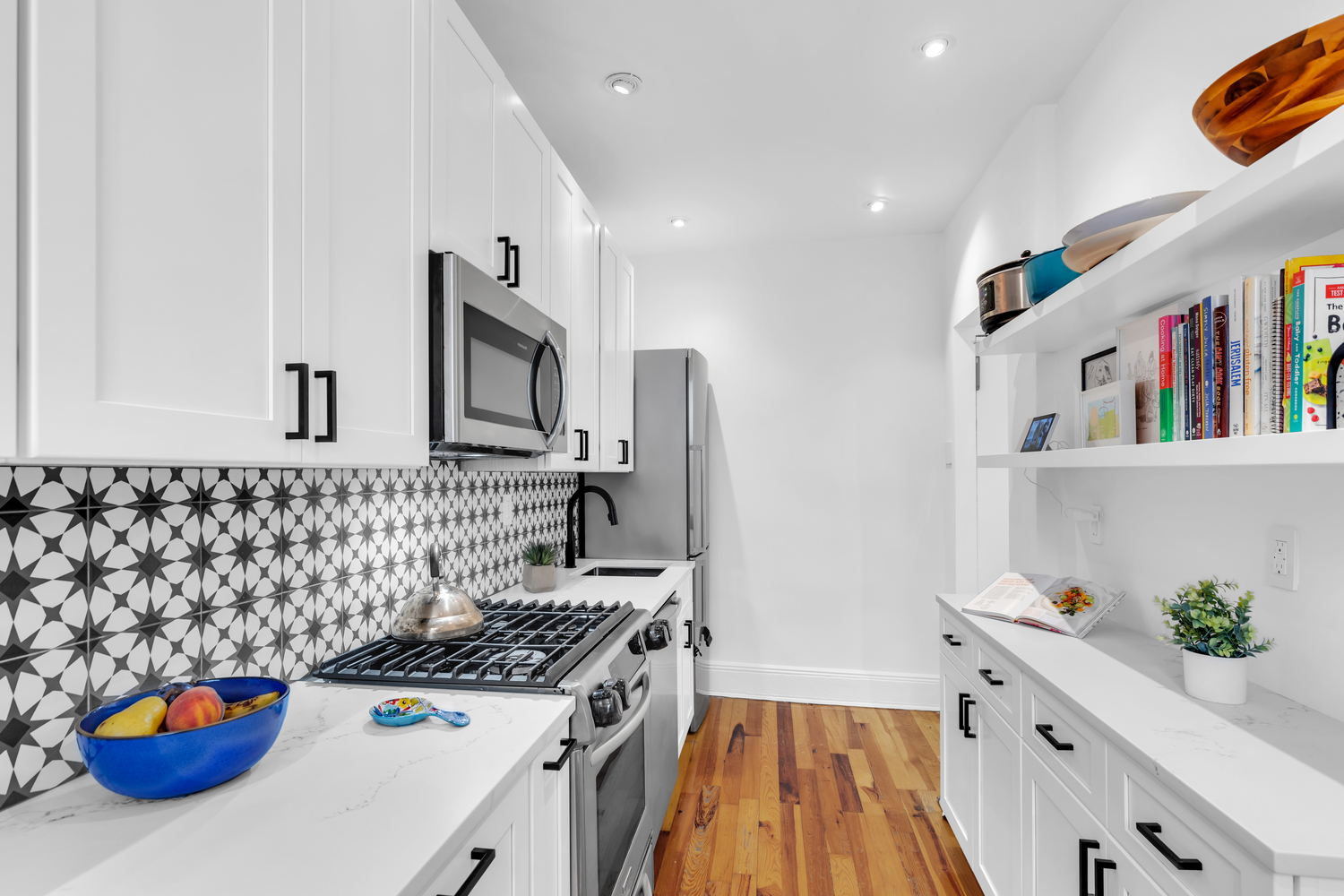 Luxury white shaker kitchen with matte black hardware, black-and-white star tile backsplash, quartz countertops, and hardwood floors – full renovation in Prospect Park Southwest, Brooklyn by SABI Construction